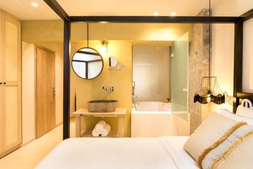 a bedroom with a bed and a tub and a mirror at C Suites in Rethymno Town