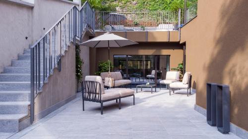 a patio with chairs and an umbrella and stairs at Le Stanze del Lago Villa Seta in Como