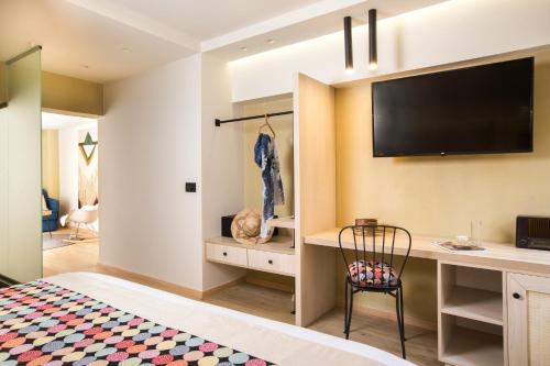 a bedroom with a desk and a television on a wall at C Suites in Rethymno Town