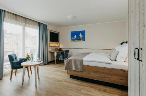 um quarto de hotel com uma cama, uma mesa e cadeiras em Hotel Alter Muschelsaal em Büsum