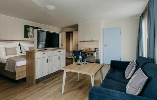 a living room with a bed and a tv and a couch at Hotel Alter Muschelsaal in Büsum