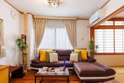 a living room with a brown couch and a table at Naha Gajumaru Apartment Hotel 301 in Naha
