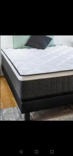 a bed with white sheets and a black pillow on it at Julie's Home in Bray-Dunes