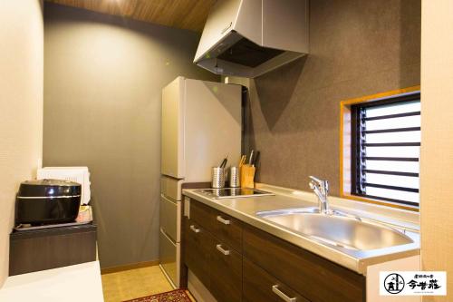 a kitchen with a sink and a refrigerator at KONJAKUSO Osaka Dotonbori "YORIAI" Penthouse Stay in Osaka