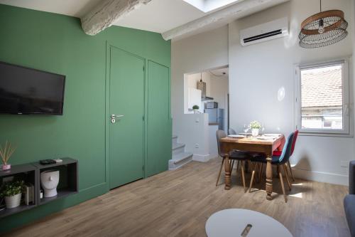 a living room with a table and a green wall at Le Chapeau Rouge au coeur du centre historique in Avignon