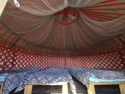 a room with a bed in a red and white tent at Yurt Camp Ali-Nur, Lake Song-Kul , Kyrgyzstan, Юрточный лагерь Али Нур, на берегу озера Сон Кол in Naryn