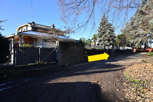 a house with a fence and a yellow arrow at B&B Parco Antico in Somma Lombardo