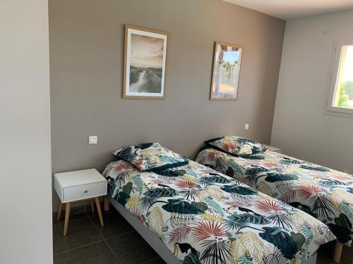 - une chambre avec 2 lits, une table et 2 photos dans l'établissement Villa Chez Géraldine Piscine chauffée, proche plage et rivière, à Lecci