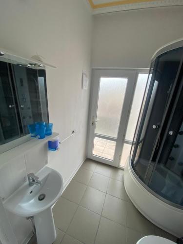 a white bathroom with a sink and a window at Vila Hubert in Baile Felix