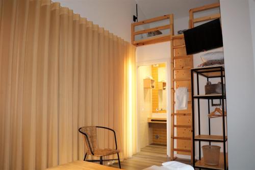 a bedroom with a bed and a chair and a curtain at Nazaré Sweet Dreams in Nazaré