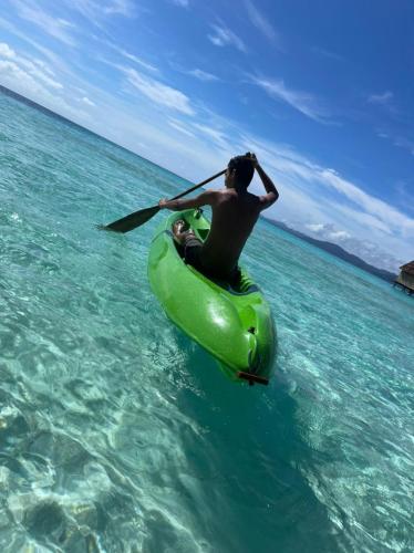 a man in a green kayak in the water at Wai Resort - Raja Ampat in Pulau Birie