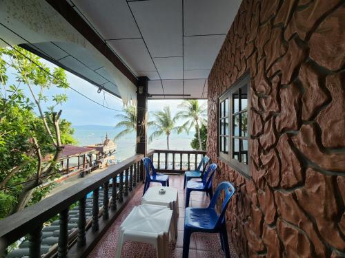 a balcony with chairs and tables and a stone wall at Coral Resort & Bungalows in Haad Rin