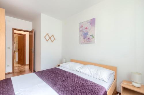 um quarto com uma cama grande e um cobertor roxo em Apartments Gilly 1 em Premantura