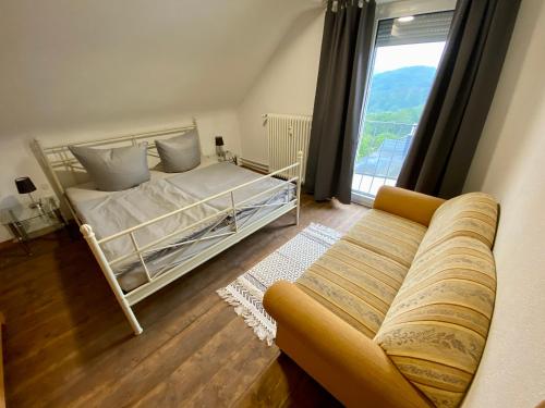1 dormitorio con cama, sofá y ventana en Ferienwohnung Ernzerhof, en Idar-Oberstein