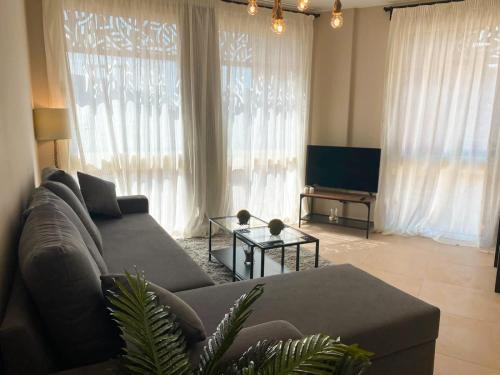 a living room with a couch and a tv at Lovely 1 Bedroom apt. At Mangroovy residence with free access to the Beach and Pools in Hurghada