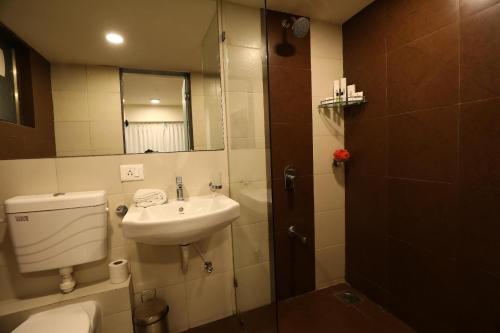 a bathroom with a sink and a toilet and a mirror at Homestays at Rajhans BELLIZA Near Airport in Surat