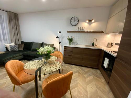 a kitchen and a living room with a table and chairs at Alėjos Apartmentai City in Druskininkai