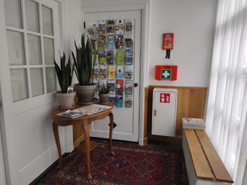 a hallway with a table and potted plants next to a door at VRYE HEERLYKHEYD ( adults only ) studio 2 in Middelburg