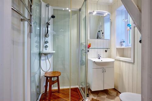 y baño con ducha, lavabo y taburete. en Nyksund House Kapellbakken 3 bedrooms with sea view, en Nyksund