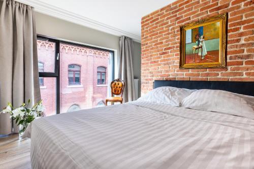 a bedroom with a large bed and a brick wall at MIRA APARTMENTS in Gdańsk