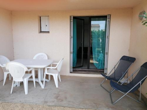 - une table et des chaises blanches sur la terrasse dans l'établissement BEIJA FLOR, au Cap d'Agde