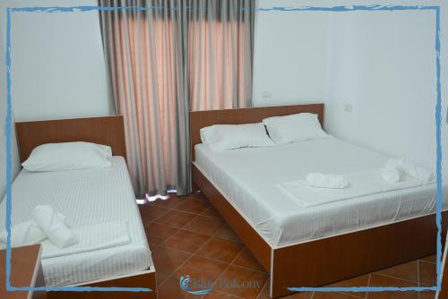 a bedroom with two beds and two windows at Blue Balcony Hotel in Golem