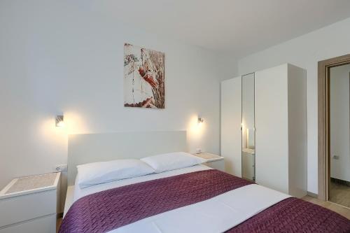 a bedroom with a bed and a painting on the wall at Apartments Gilly 2 in Premantura