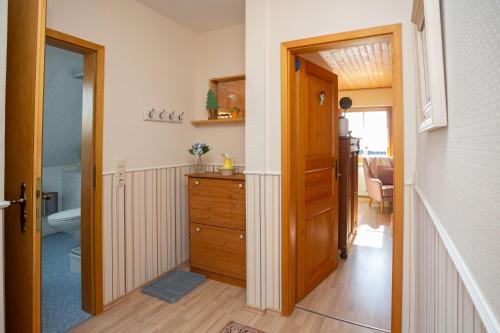 un couloir avec une commode en bois et une salle de bains. dans l'établissement Ferienwohnung Anemone mit Bergblick, à Braunlage