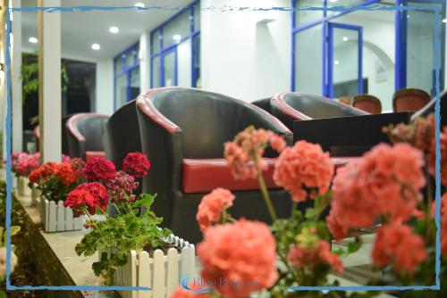 a row of chairs with red flowers on a table at Blue Balcony Hotel in Golem