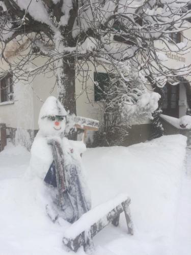 a snowman sitting on a bench in the snow at Arlenheim in Sankt Anton am Arlberg