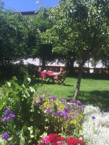 a woman sitting at a table in a garden with flowers at Arlenheim in Sankt Anton am Arlberg