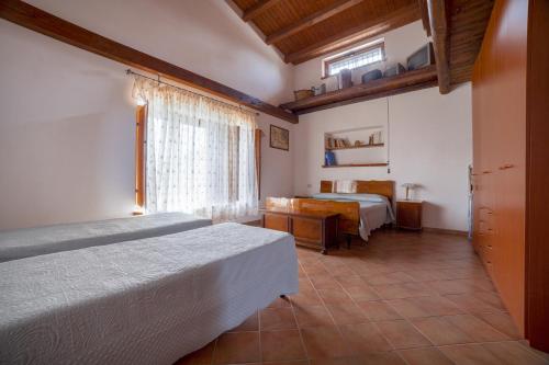 1 dormitorio con 2 camas y ventana en Il Prato degli Ulivi, en Rocca Imperiale