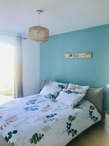 une chambre avec un lit avec un mur bleu dans l'établissement Au petit bonheur de Claire et Jo, à La Chapelle-Caro