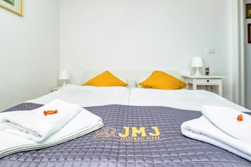 a bed with white towels and orange pillows on it at JMJ PH Nono in Piran