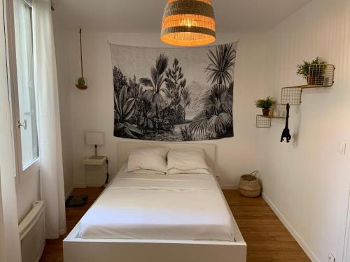 un lit dans une chambre avec un tableau sur le mur dans l'établissement Le Sainte Croix, beau T2 lumineux à 800 m de la gare St Jean, à Bordeaux