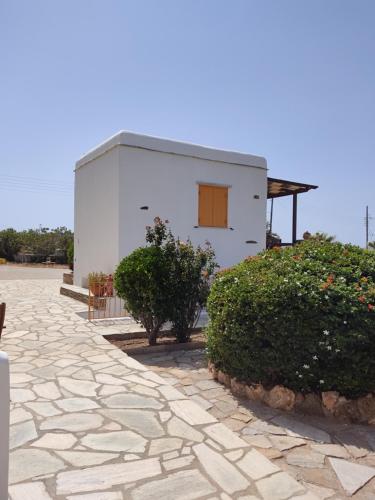 a small white building with a stone walkway at Aigaio Studios tinos in Tinos Town