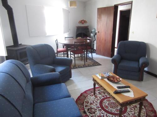 ein Wohnzimmer mit blauen Stühlen und einem Tisch in der Unterkunft Casa Eira do Povo in Vale de Colmeias