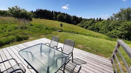 una mesa de cristal y sillas en una terraza de madera en Chata Luční en Klíny