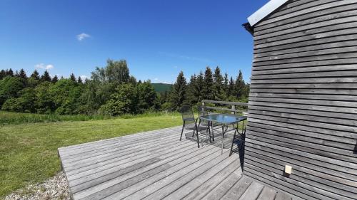 a wooden deck with a table and chairs on it at Chata Luční in Klíny
