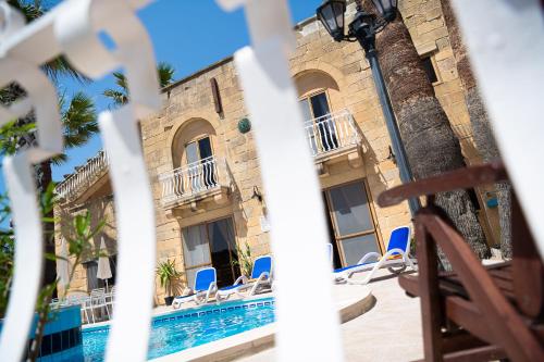 a resort with a swimming pool and blue chairs at Blossom Farmhouses in Għasri