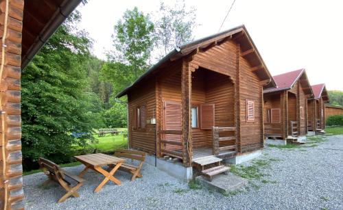 a row of wooden lodges with a table and benches at Gyopar Wooden Houses in Izvoare