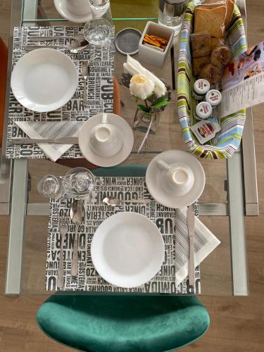 a table with white plates and a green chair at Casa Mar - B&B - in Terracina