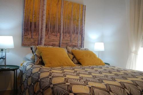 マラガにあるAcogedor apartamento cerca del centro histórico de Málagaのベッドルーム1室(黄色い枕とランプ2つ付)
