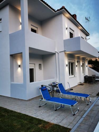 a white house with blue chairs on a patio at BIG BLUE HOTEL in Amaliápoli