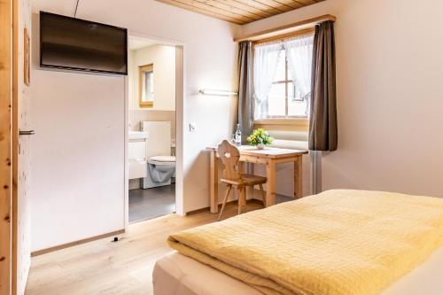 a bedroom with a bed and a desk and a bathroom at Hotel Landgasthof Staila in Fuldera