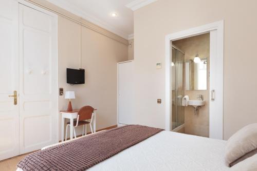 a white bedroom with a bed and a sink at Hostal Oliva in Barcelona