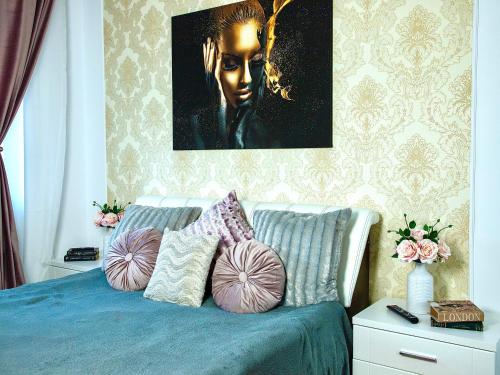 a bedroom with a bed with pillows and a painting at Style apartment in Mamaia Nord
