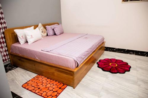 a bed in a room with a red flower on the floor at Kikis Court Resort in Hohoe