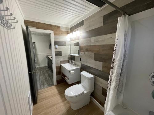 a bathroom with a toilet and a wooden wall at PEI Cottage Rental in Borden-Carleton