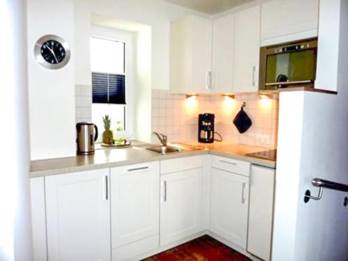 - une cuisine blanche avec des placards blancs et un évier dans l'établissement Seebox Appartment 3, à Norderney